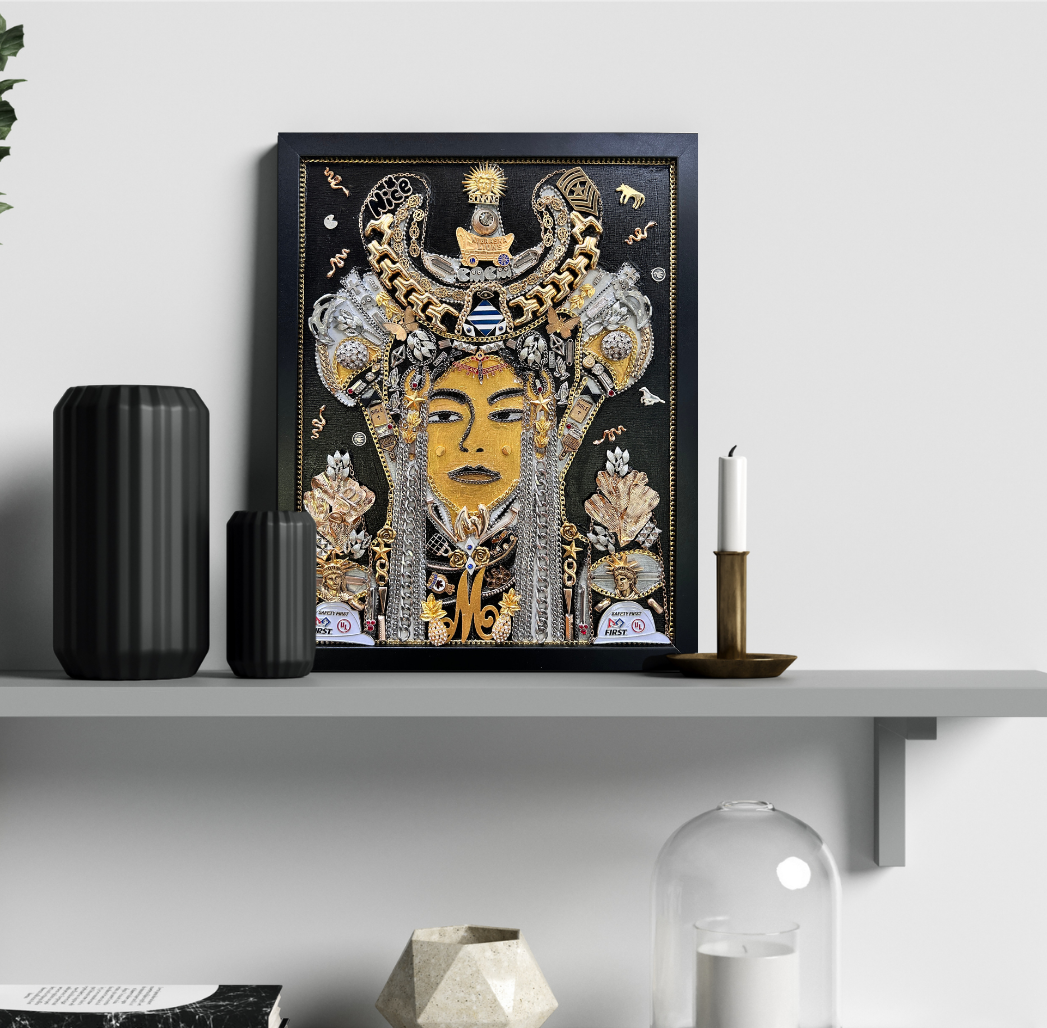 A framed art print featuring a stylized golden face with an ornate headdress, displayed on a gray floating shelf in a modern room setting with decorative vases and a candle holder.